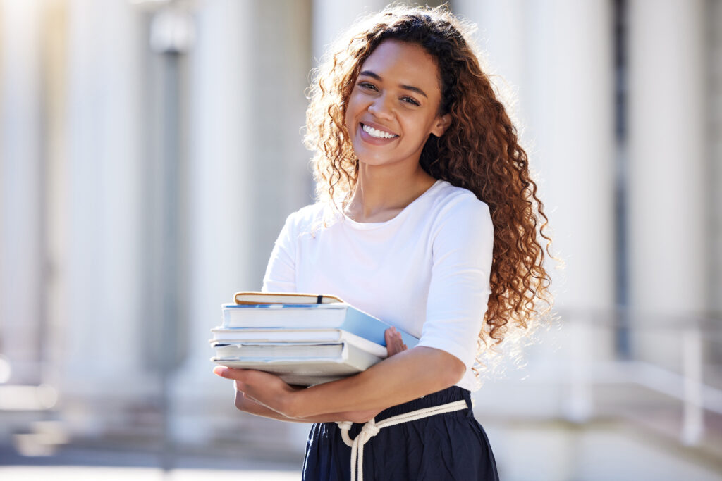Young woman carrying her schoolbooks outside at college.